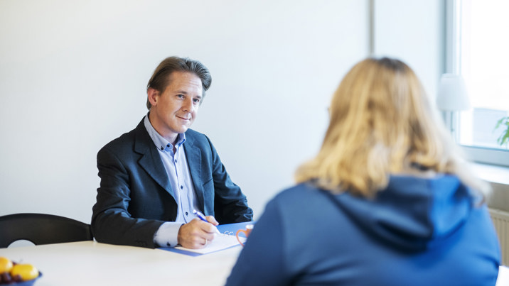 Jurist i kostym och dokument framför sig diskuterar med klient över bord
