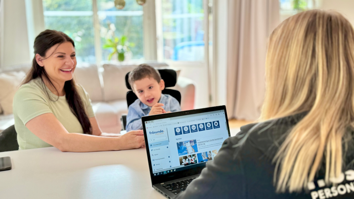 Mamma och son i rullstol möter assistansrådgivare som har information på laptop